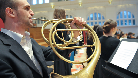 Man playing horn in orchestra